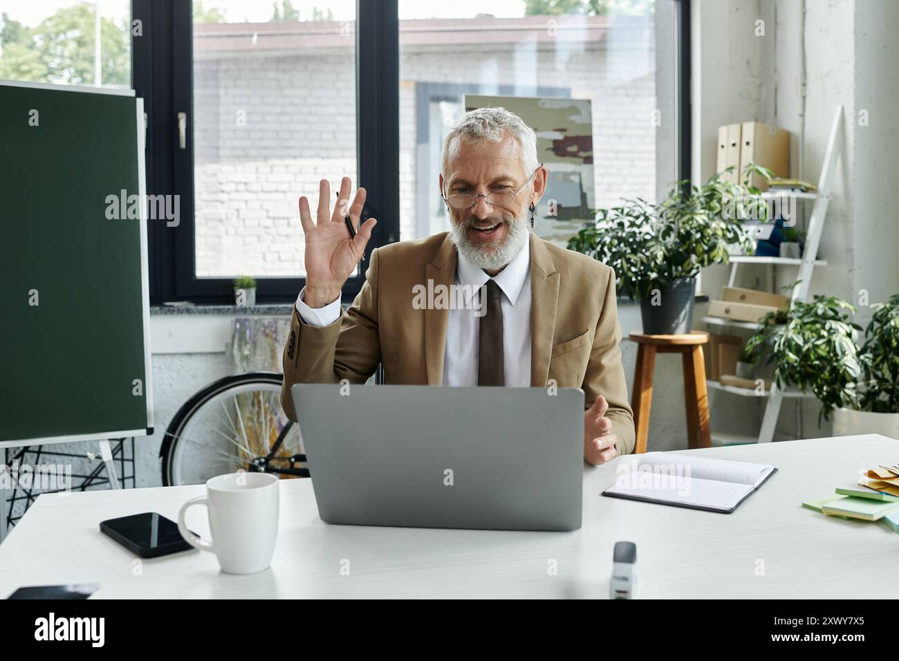 Ein reifer Lehrer mit Bart winkt seinen Schülern während eines Online-Kurses zu, lgbtq-Mitglied Stockfoto