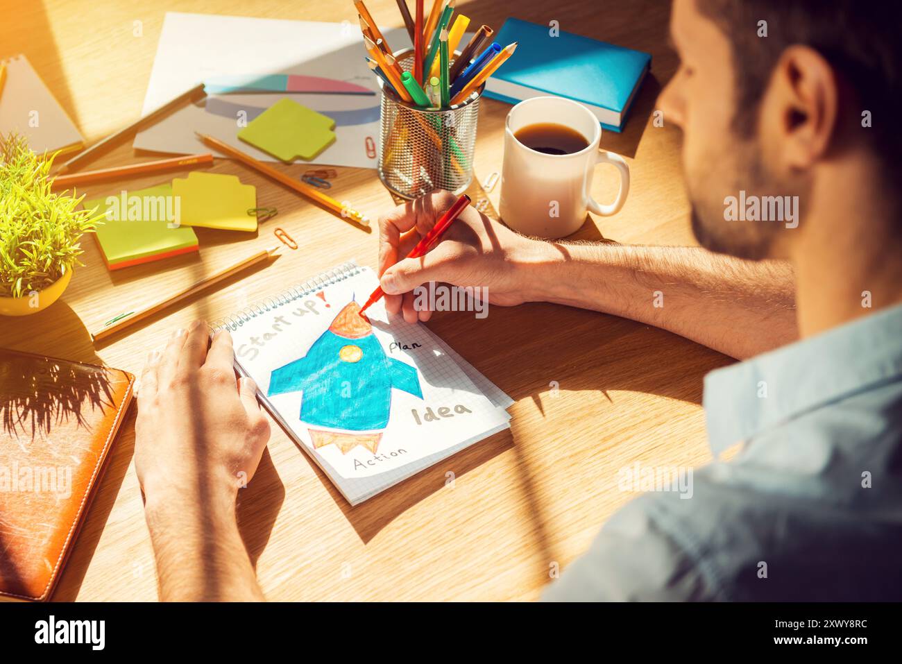 Gerade inspiriert. Nahaufnahme eines Mannes von oben, der auf Papier skizziert, während er an seinem Arbeitsplatz sitzt Stockfoto