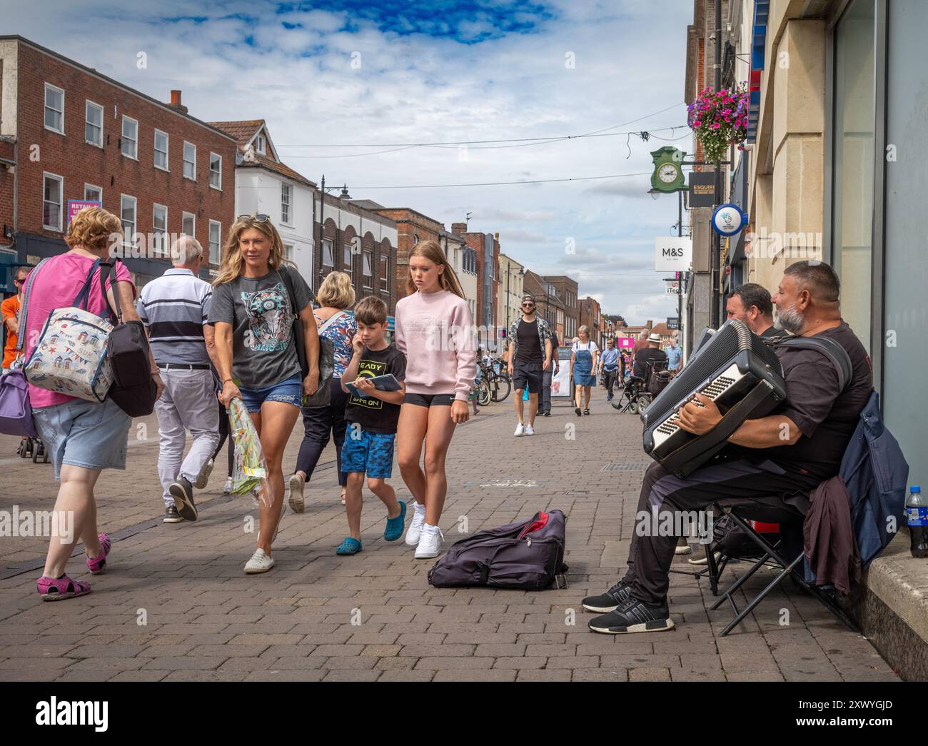 In der Northbrook Street, dem Zentrum von Newbury, Berkshire, England, geht man an zwei eingewanderten Buskern vorbei, die Akkordeane spielen Stockfoto