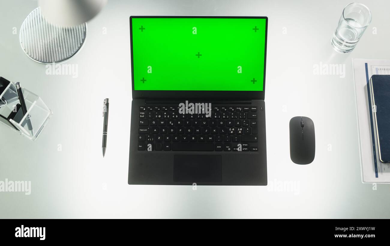 Top-Down-Ansicht: Laptop-Computer mit Mock-Up-Green-Screen-Chromakey-Display mit Motion Tracker auf einem Schreibtisch in einer modernen Firmenzentrale. Fotovorlage für Werbematerial Stockfoto