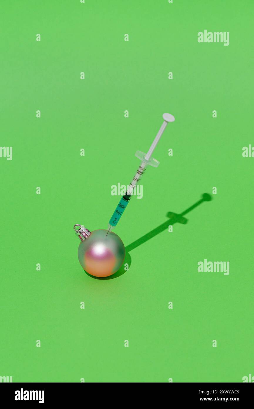 Rosafarbene Weihnachtskugel, die durch Injektion auf grünem Hintergrund Farbe in tiffany-Blau ändert. Kreatives Weihnachts- und Neujahrskonzept. Stockfoto