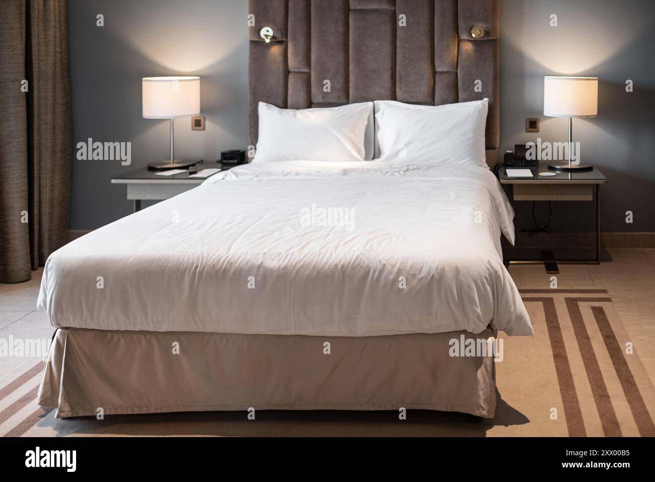 Stilvolles Schlafzimmer mit Doppelbett. Moderne Schlafzimmereinrichtung mit einem Hauptbett mit zwei Nachttischlampen. Großes, komfortables Doppelbett in eleganter Atmosphäre Stockfoto