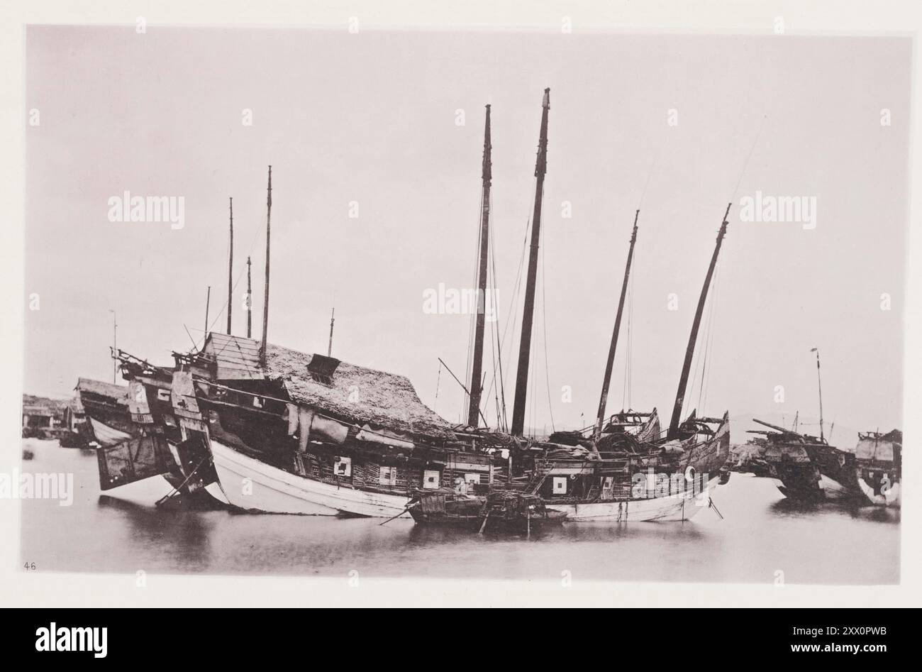 Vintage-Foto von alten Dschunks. Illustrationen von Qing China, 1875 interessante Schiffe sind die alten wetterbefallenen Dschunken, die vor Anker im Kanton-Fluss liegen und warten, bis der Monsun günstig ist, um ihre Reise fortzusetzen. Das übliche Ziel solcher Dschunken ist einer der Häfen an der chinesischen Küste, oder am weitesten entfernten, Siam, Java, Borneo, oder die Straße von Malakka. An ihren Anlegeplätzen, wie auf dem Foto dargestellt, scheinen diese riesigen, ungeschickten Schiffe wie Wohnplätze in der Mitte des Baches zu sein, die durch feste Fundamente am Flussbett befestigt sind, aber wenn sie voll für das Meer gerüstet sind, sehen sie gut aus und machen manchmal sogar Goos Stockfoto