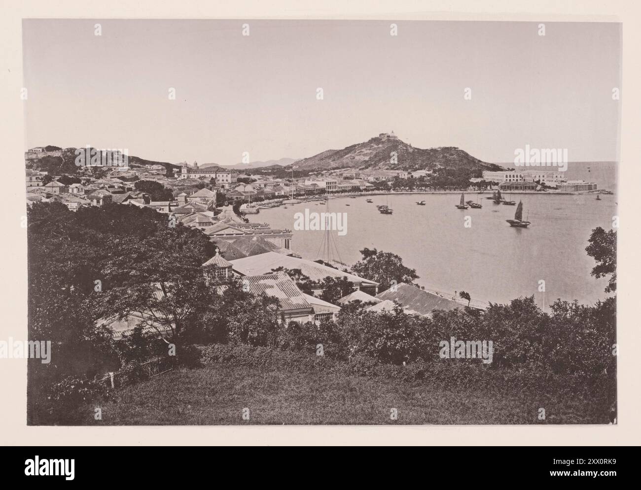 Vintage-Foto von Macau (Macau). Illustrationen von Qing China, 1875 ... die Hauptresidenzen liegen vor der Bucht, um die eine breite Kutschenfahrt fährt, die als Praya Grande bekannt ist. Dieses Bild wurde vom Hügel oberhalb der Bishop's Bay am südlichen Ende der Praya aufgenommen. Der Innenhafen befindet sich auf der nordwestlichen Seite der Halbinsel, hier befindet sich der älteste Teil der Stadt. Eine Reihe von engen, schmuddeligen Gassen führen von der Praya zu den Hauptstraßen im oberen Teil der Stadt; und hier tragen die Häuser ein interessantes, antikes Aussehen, stark getarnt, wie Stockfoto
