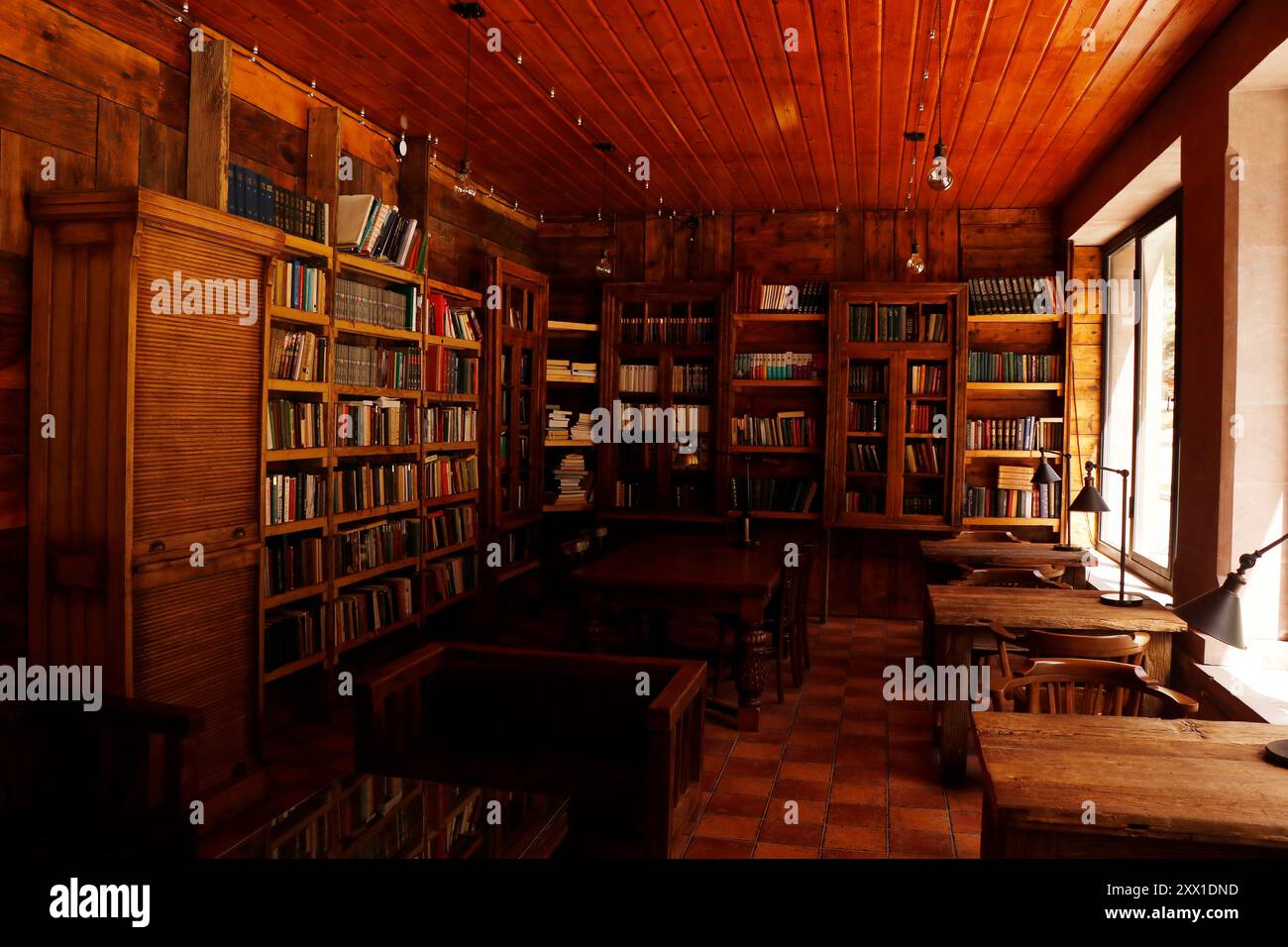Traditionelle Bibliothek mit Holzregalen, Tisch und Stuhl in bernsteinfarbenem Vintage-Schatten in georgia Stockfoto