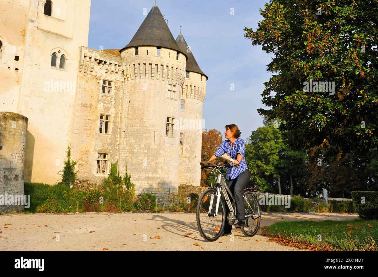 Junge Frau radelt vor dem Schloss St-Jean, Nogent-le-Rotrou, Parc naturel Regional du Perche, Eure-et-Loir, Cengre-Val-de-Loire, Frankreich Stockfoto