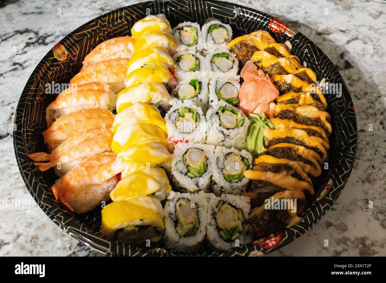 Mehrfarbiges Sushi mit einem Stück Ingwer auf einem schwarzen japanischen Teller, Nahaufnahme abgebildet Stockfoto