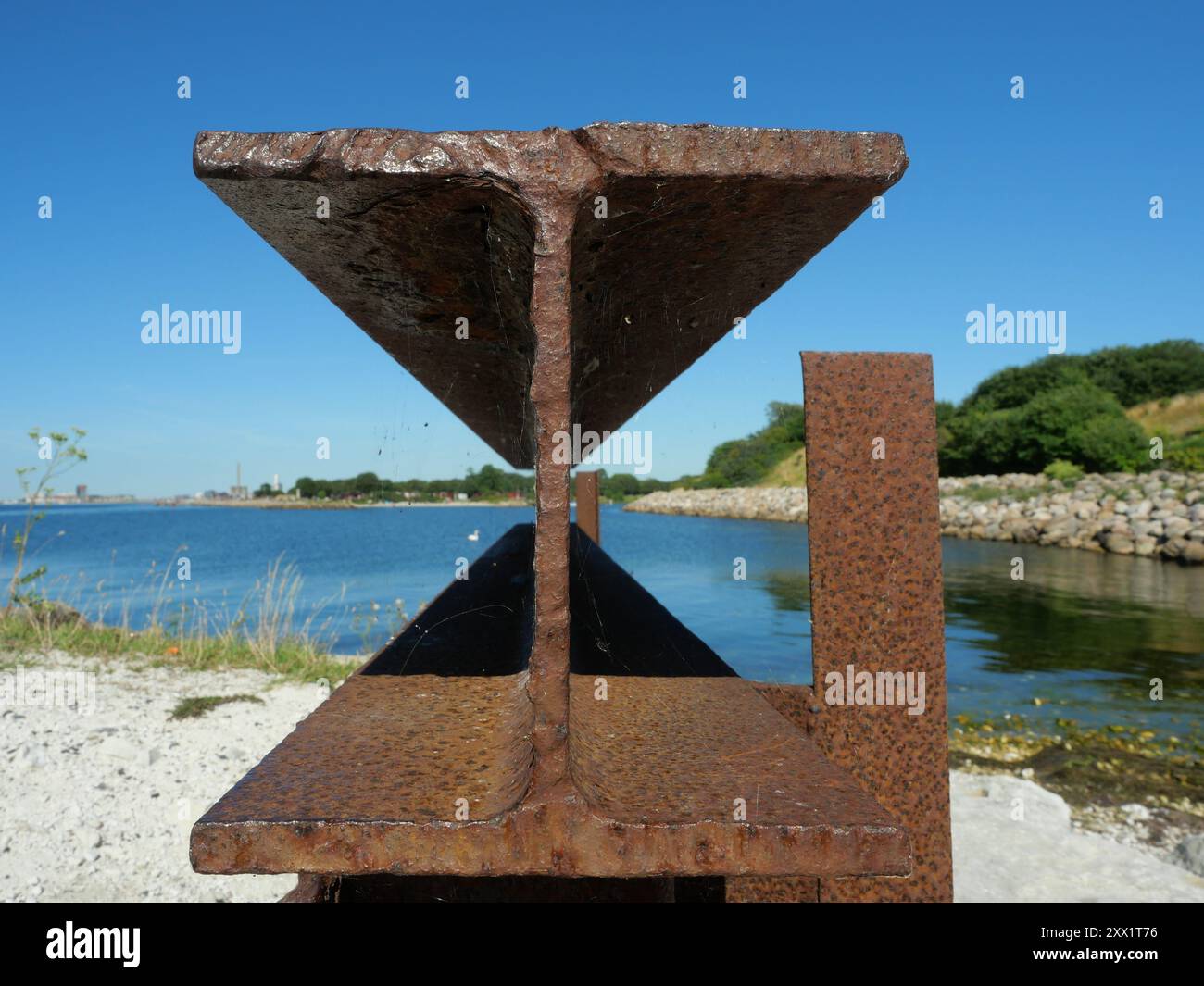 Rostiger Stahlbalken mit Doppel-T-Profil, der von einem alten Pier überliefert ist, symbolisiert industrielle Relikte und die Tragkraft vergangener Bauwerke. Stockfoto