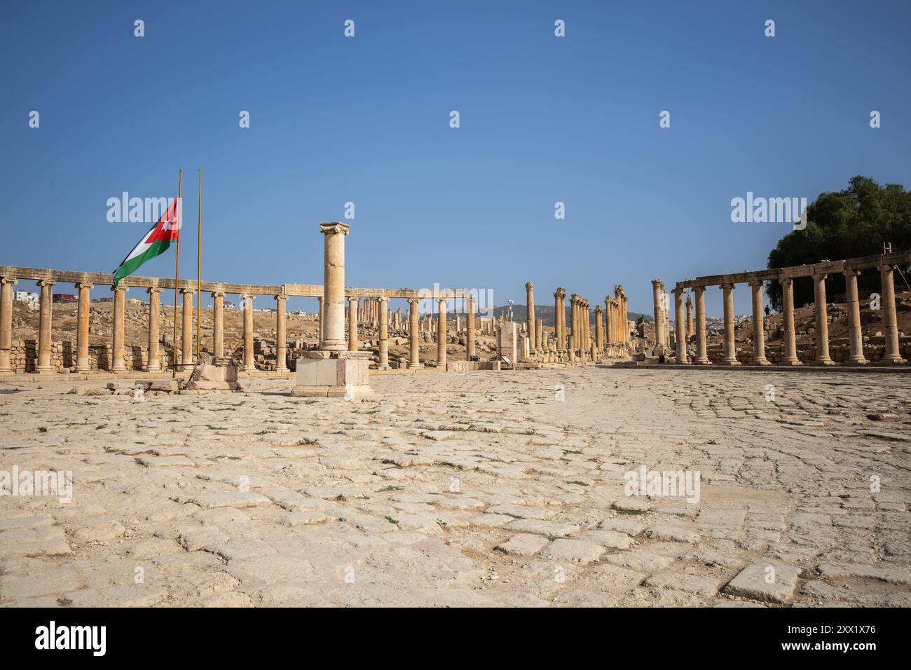 Das Oval Forum und Cardo Maximus im antiken Jerash. Historisches Wahrzeichen der römischen Architektur mit jordanischer Flagge in Nordjordanien. Stockfoto