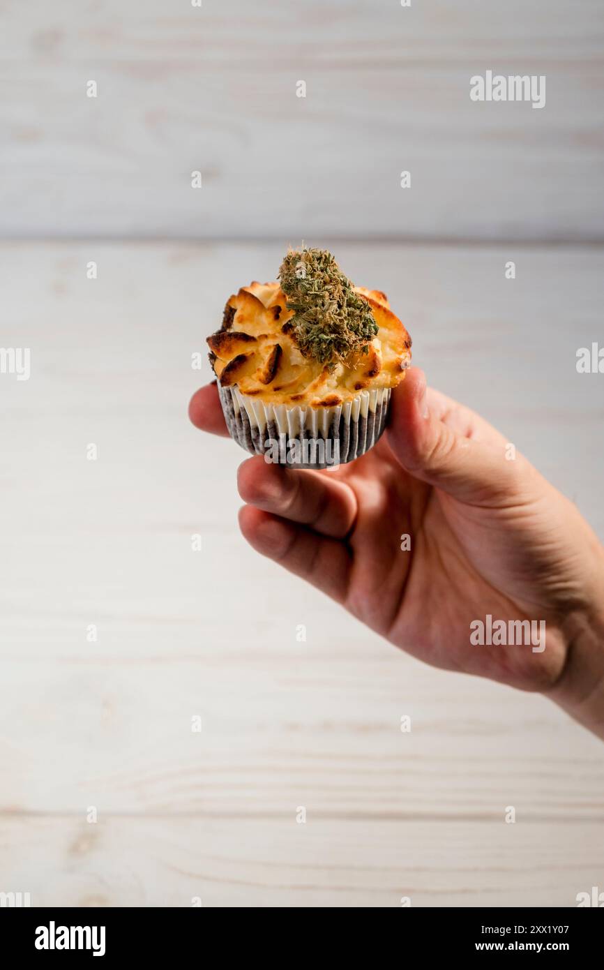 Hand hält Kuchen mit medizinischen Marihuana-Knospen, Nahaufnahme. Alternative Dessert- und Heilkräuterkonzepte Stockfoto