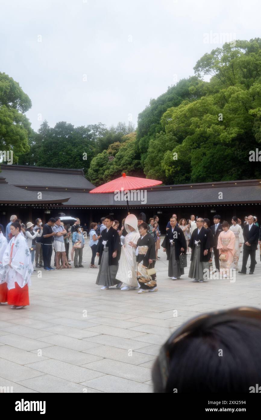 Traditioneller Shinto-Hochzeitszug am Meiji-Schrein in Tokio, Japan, unter einem roten Schirm. Stockfoto