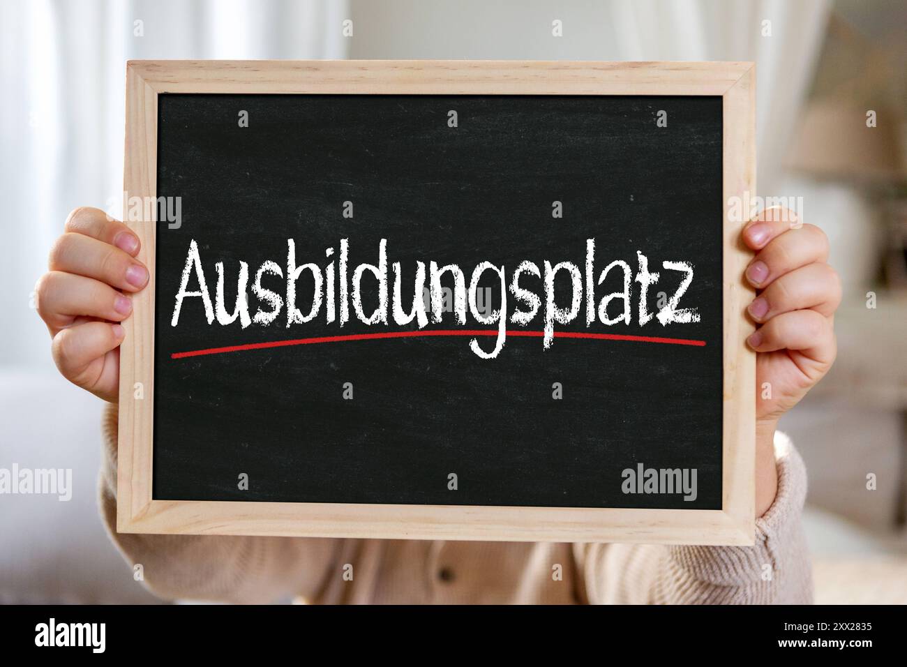 21. August 2024: Trainingsplatz, Schriftzug auf einem Brett, der von einem Jungen gehalten wird. FOTOMONTAGE *** Ausbildungsplatz, Schriftzug auf einer Tafel gehalten von einem Jungen. FOTOMONTAGE Stockfoto