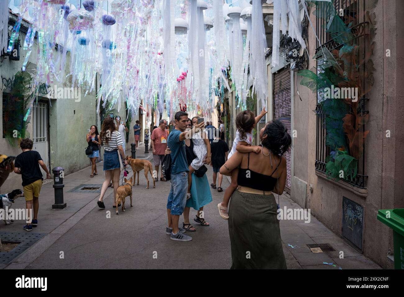 Barcelona, Spanien. August 2024. Touristen machen Fotos während der Veranstaltung „Fiesta Mayor de Gracia“ im Stadtteil Gracia. Mit mehr als 18 Millionen Touristen, die 2024 Barcelona besuchen werden, hat die Stadt Schwierigkeiten, ein Gleichgewicht zwischen den wirtschaftlichen Vorteilen des Tourismus während der Tourismussaison und der Notwendigkeit zu finden, die Stadt für die Einwohner lebenswert zu halten, die dem Massentourismus und der Ausbeutung der Stadt durch die Tourismusbranche feindselig gegenüberstehen. Quelle: SOPA Images Limited/Alamy Live News Stockfoto