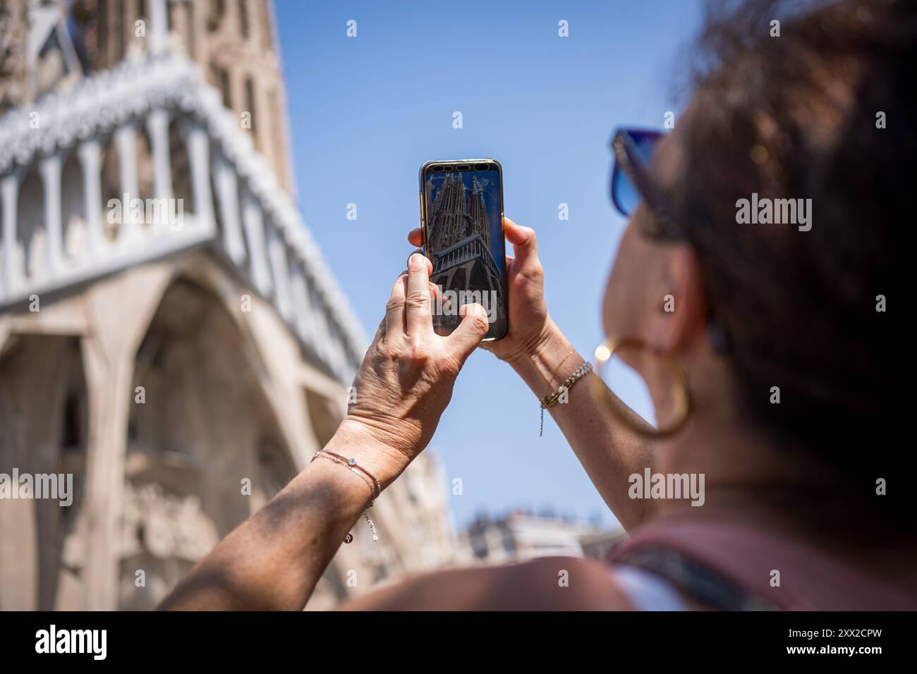 Barcelona, Spanien. August 2024. Touristen machen Fotos von der Kirche Sagrada Familia im Stadtzentrum. Mit mehr als 18 Millionen Touristen, die 2024 Barcelona besuchen werden, hat die Stadt Schwierigkeiten, ein Gleichgewicht zwischen den wirtschaftlichen Vorteilen des Tourismus während der Tourismussaison und der Notwendigkeit zu finden, die Stadt für die Einwohner lebenswert zu halten, die dem Massentourismus und der Ausbeutung der Stadt durch die Tourismusbranche feindselig gegenüberstehen. Quelle: SOPA Images Limited/Alamy Live News Stockfoto