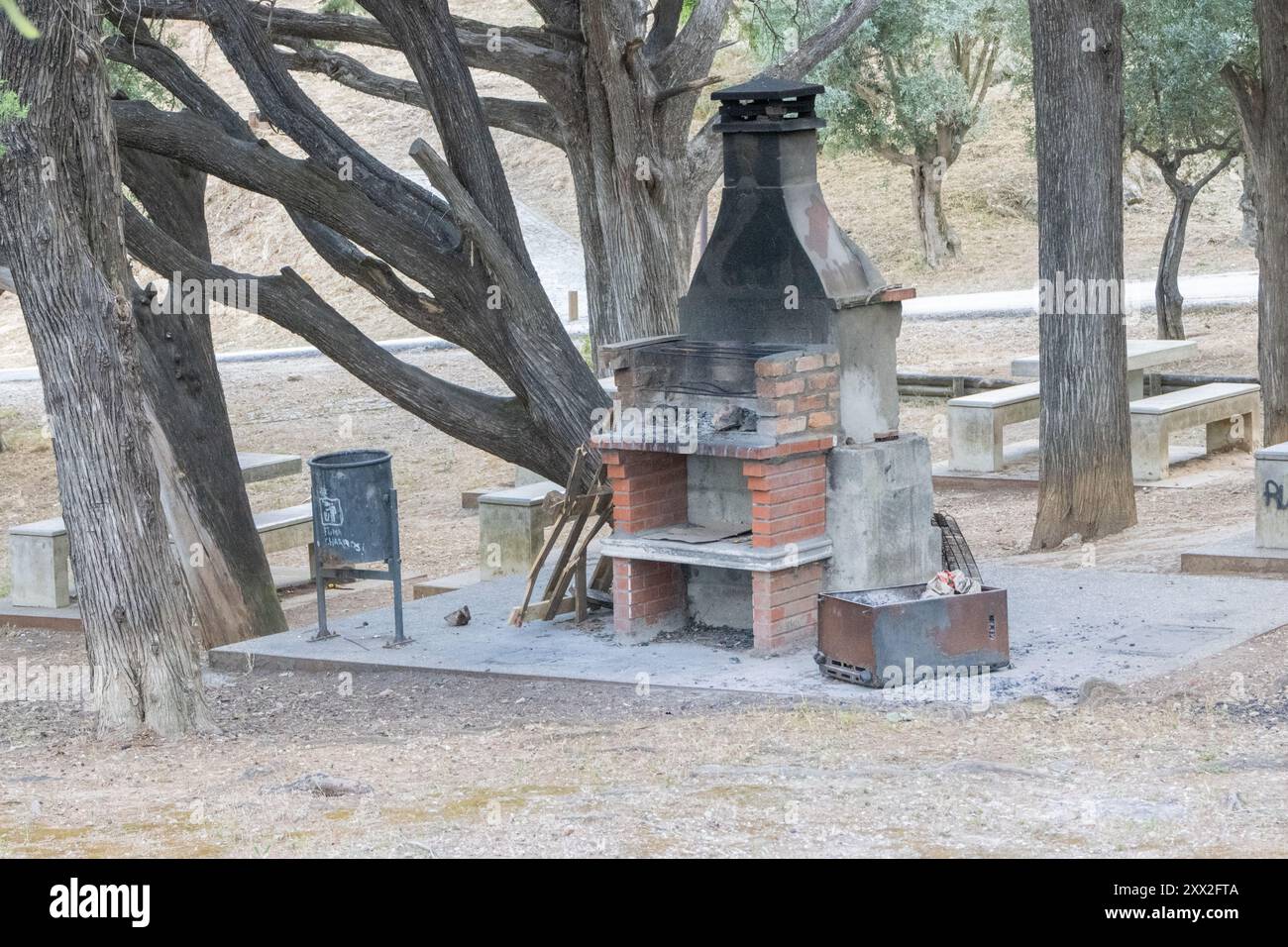 Alter Steingrill mit Kamin in einem öffentlichen Ruhebereich des Parks, an dem niemand an einem sonnigen Tag herumsteht Stockfoto