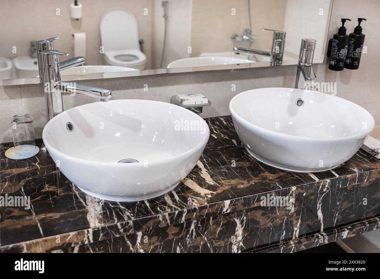 Badezimmer moderner Kosmetikbereich mit zwei runden Keramikwaschbecken. Ein moderner Kosmetikbereich im Bad mit zwei ovalen Waschbecken und einem Spiegel. Minimalistisches Bad Stockfoto