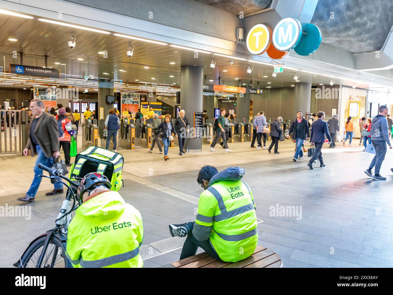 Die Fahrer von Uber Eats machen eine Mittagspause in Chatswood Sydney mit Elektro-E-Bike neben ihnen, in hiviz gelben Jacken, Chatswood, Sydney Stockfoto