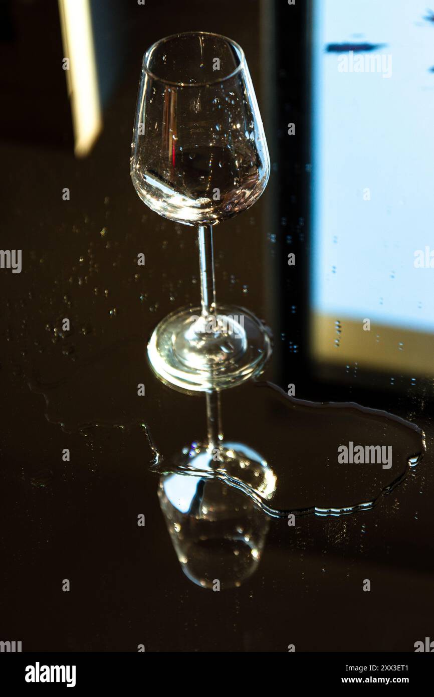 Weinglas mit Reflexion auf dem Spiegel mit Tropfen herum Stockfoto