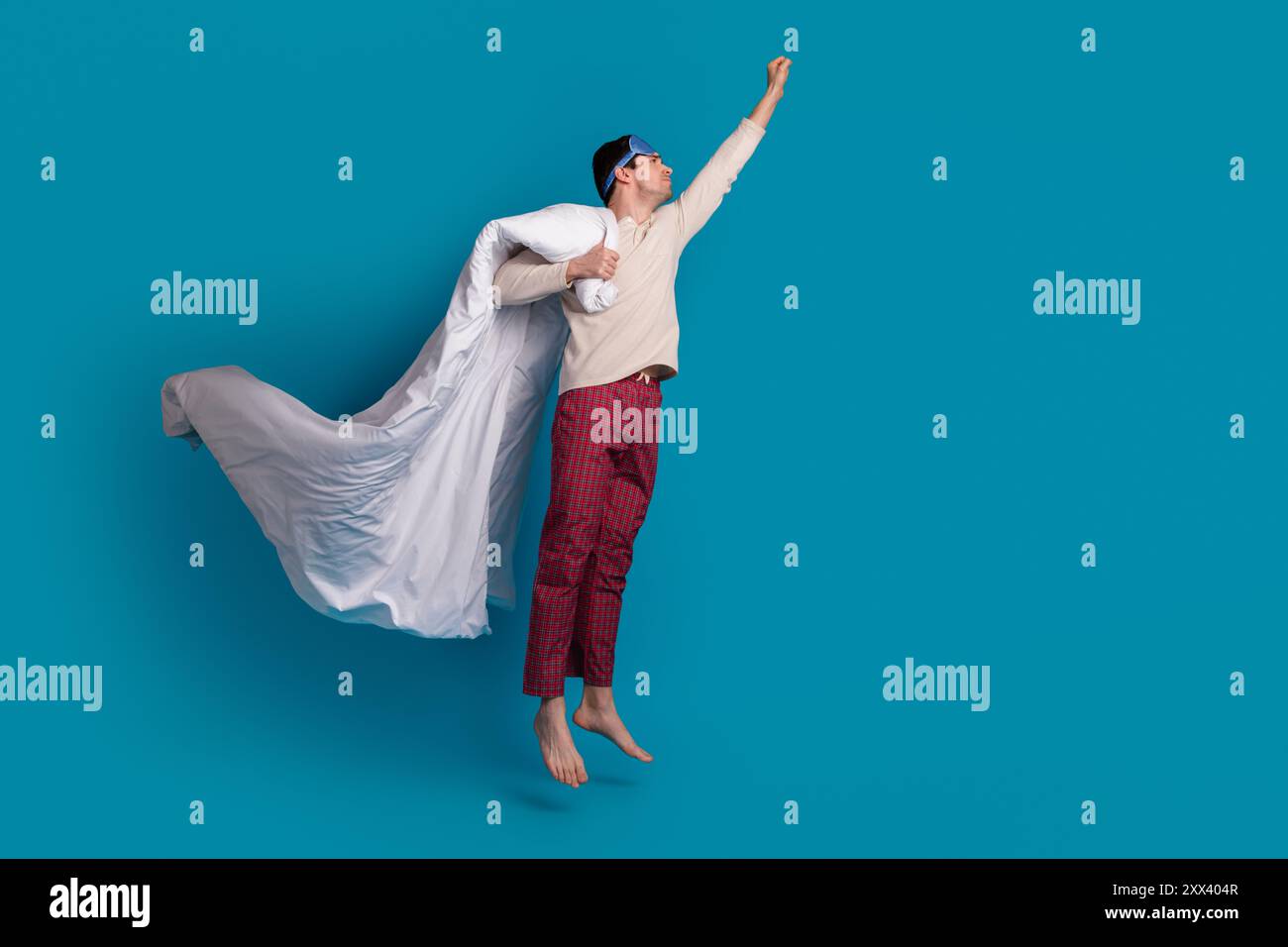 Ganzkörperfoto des attraktiven jungen Mannes fliegende Superhelden gekleidete Pyjama Sleepover Gute Nacht isoliert auf blauem Hintergrund Stockfoto