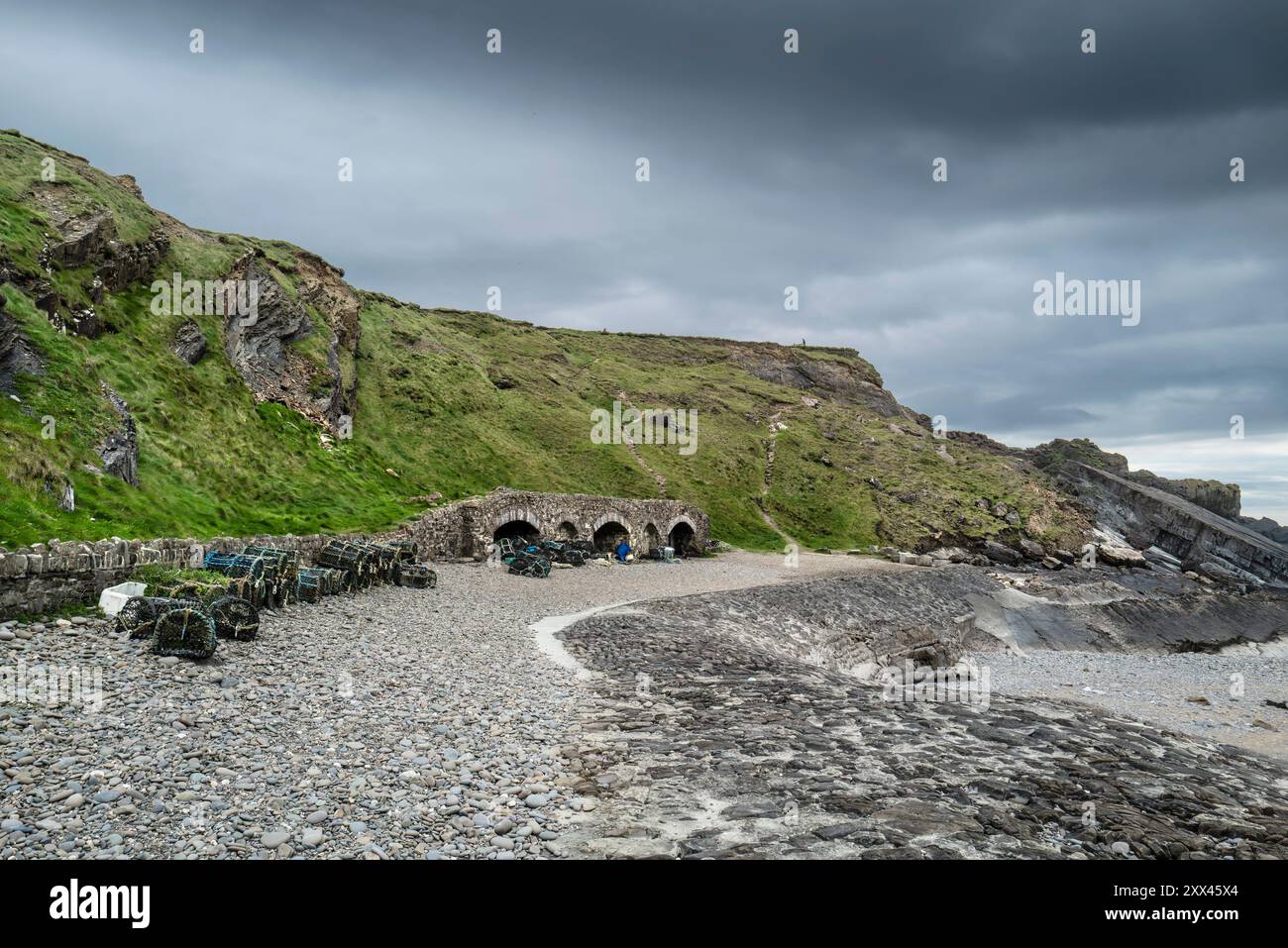 Hummertöpfe werden in der Nähe von Steinbögen an einem Kiesstrand in Bude in Cornwall, Großbritannien, gelagert. Stockfoto