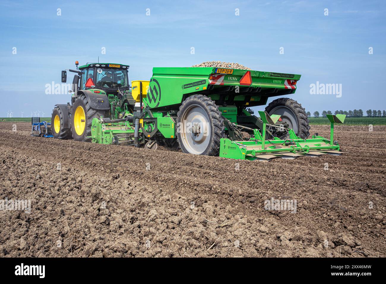Ein Landwirt pflanzt mit einem Traktor und einem Anbaugerät Kartoffeln auf den fruchtbaren Feldern in den Niederlanden. Stockfoto