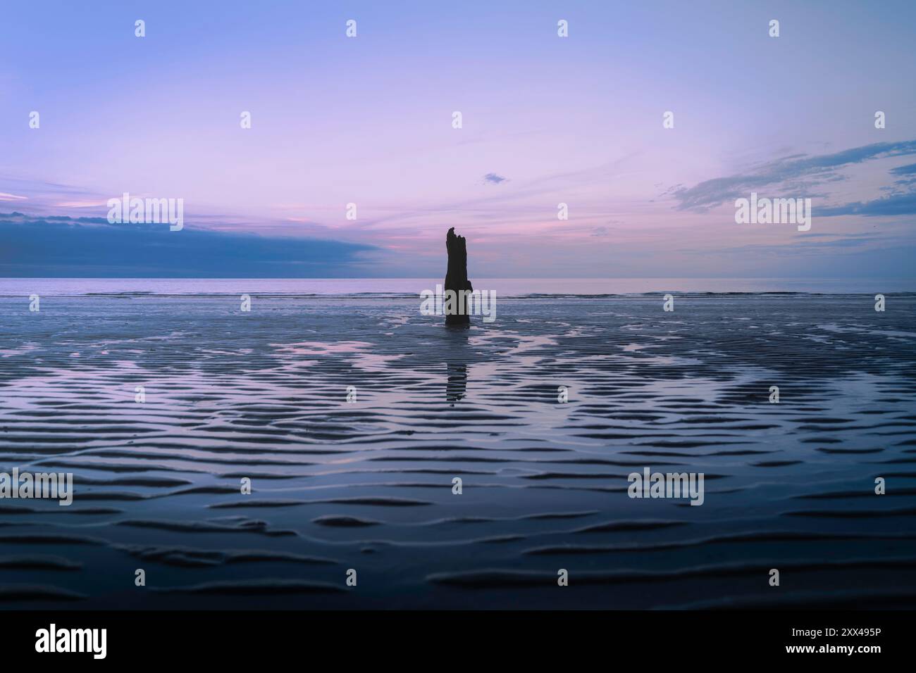 Minimalistisches, dämmerliches Meeresbild mit Silhouette und gewelltem Sand, Ozean und Wasserreflektionen – eine ruhige und stimmungsvolle Küstenlandschaft in norfolk, ruhig A Stockfoto