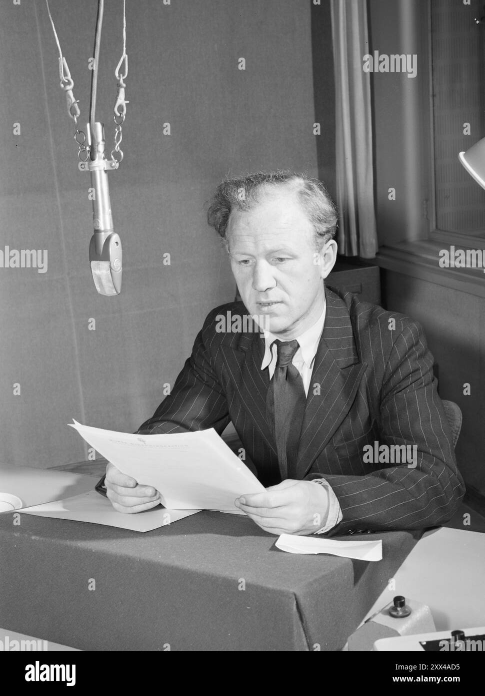 Aktuell 12–1949: Famous Voices in Broadcasting – Programmsekretär Hartvig Kiran war vor dem Krieg ein Halloman. Auch er gehörte zu den Stimmen aus London während des Krieges. Jetzt ist er einer von denen, die uns die Nachrichten vorlesen. Er arbeitet auch viel mit dem Berichtsmaterial. Er ist typischerweise Aalgeräusche und spricht schnell und klar. Foto; aktuell / NTB ***FOTO NICHT VERARBEITET*** dieser Bildtext wird automatisch übersetzt Stockfoto