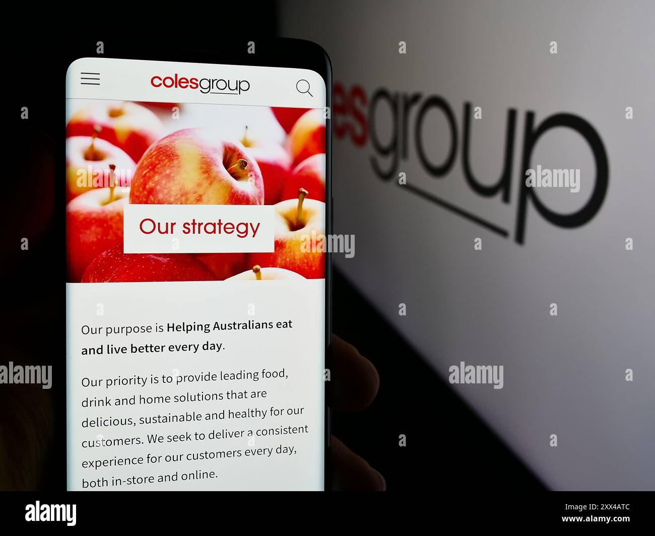 Person, die ein Mobiltelefon hält, mit der Webseite des australischen Einzelhandelsunternehmens Coles Group Limited vor dem Logo. Konzentrieren Sie sich auf die Mitte des Telefondisplays. Stockfoto
