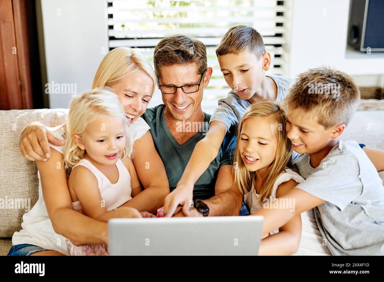 Mutter, Vater und Kinder auf der Couch mit Laptop, Online-Cartoon und Abonnement mit Verbindung. Familienheim, Mutter und Vater mit Kindern zur Filmwahl Stockfoto