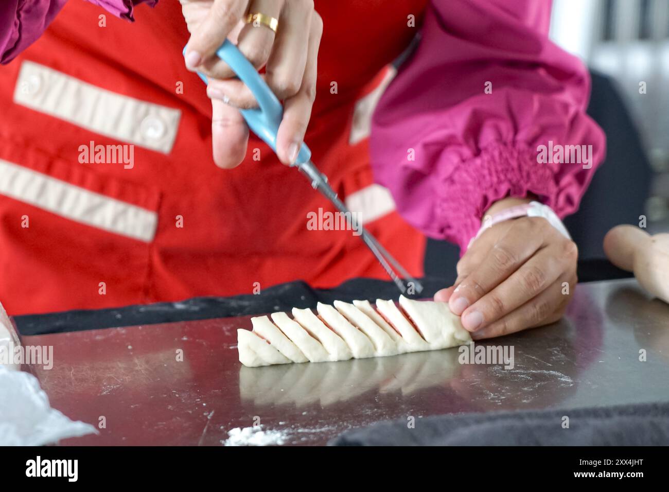Eine Frau, die einen Wurstteig formt, indem sie mit einer Schere schneidet Stockfoto