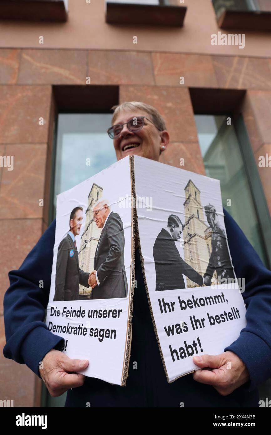 Eine Demonstrantin hält zwei Schilder mit Fotos von AfD-Politiker Björn Höcke und Bundespräsident Frank-Walter Steinmeier am Tag von Potsdam und der Aufschrift die Feinde unserer Demokratie sagen Danke sowie von Reichskanzler Adolf Hitler und Reichspräsident Paul von Hindenburg am Tag von Potsdam und der Aufschrift Ihr bekommt, was Ihr bestellt während einer Kundgebung gegen die Eröffnung des wiederaufgebauten Turms der Garnisonkirche in Potsdam, 22. August 2024. Eröffnung Garnisonkirche Potsdam *** Ein Demonstrant hält zwei Schilder mit Fotos von AfD-Politiker Björn Höcke und Bundespräsident F Stockfoto