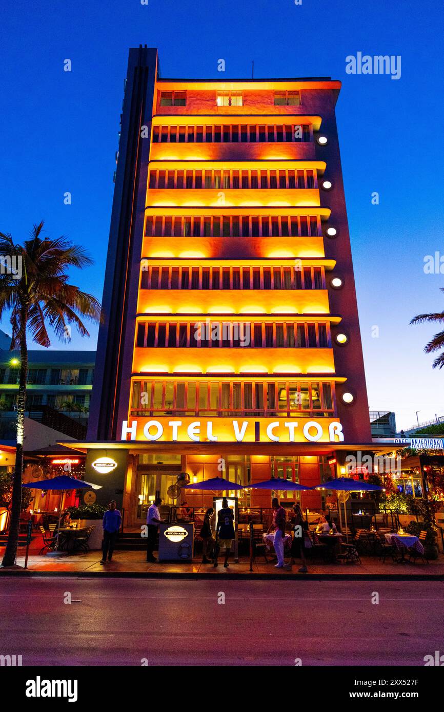 Außenansicht des Hotel Victor und beleuchtete Art déco-Gebäude und Restaurants am Ocean Drive, Miami Beach, Florida, USA Stockfoto