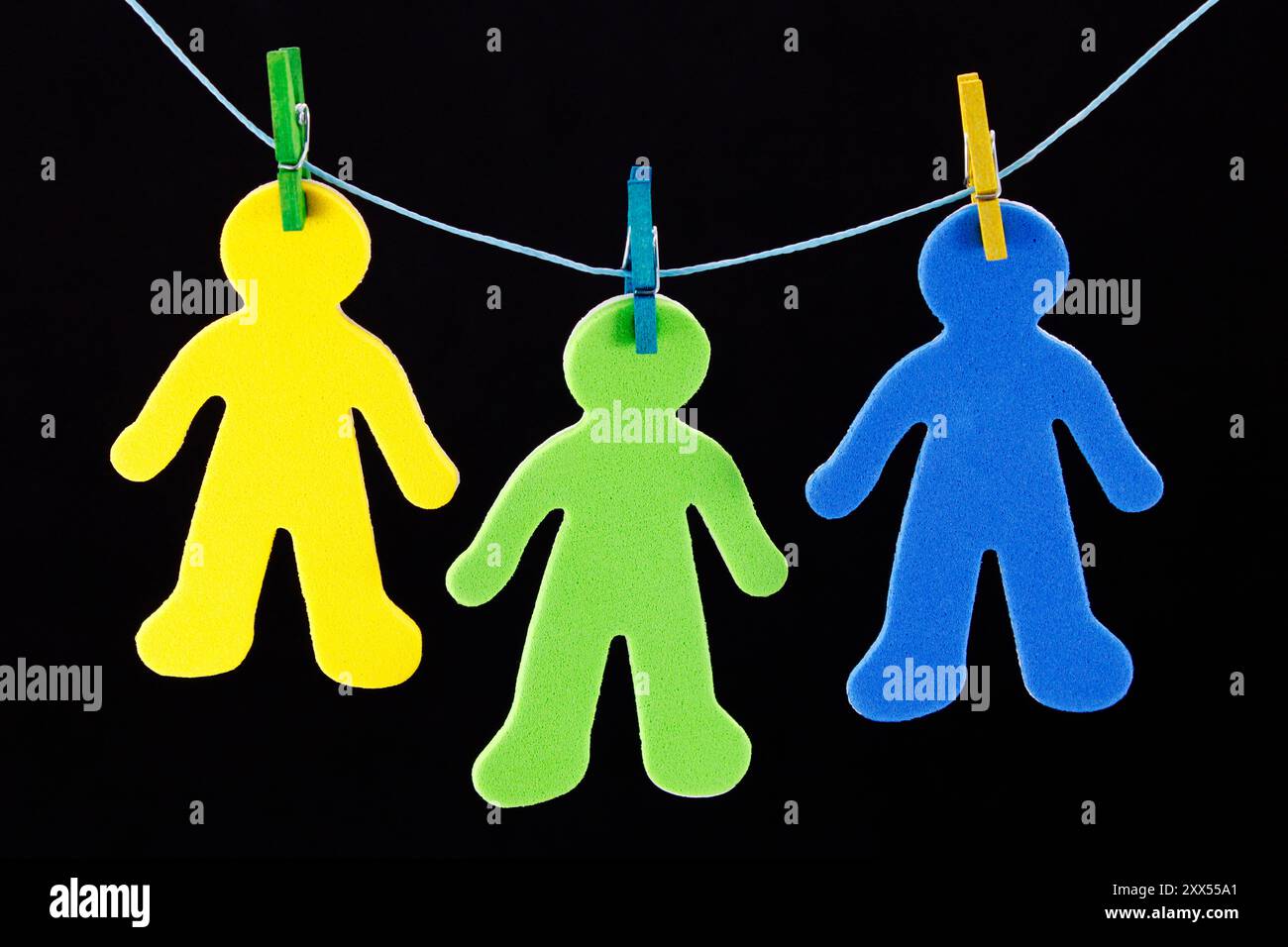 Drei bunte Silhouetten von Menschen, die mit Kleiderschalen hängen Stockfoto