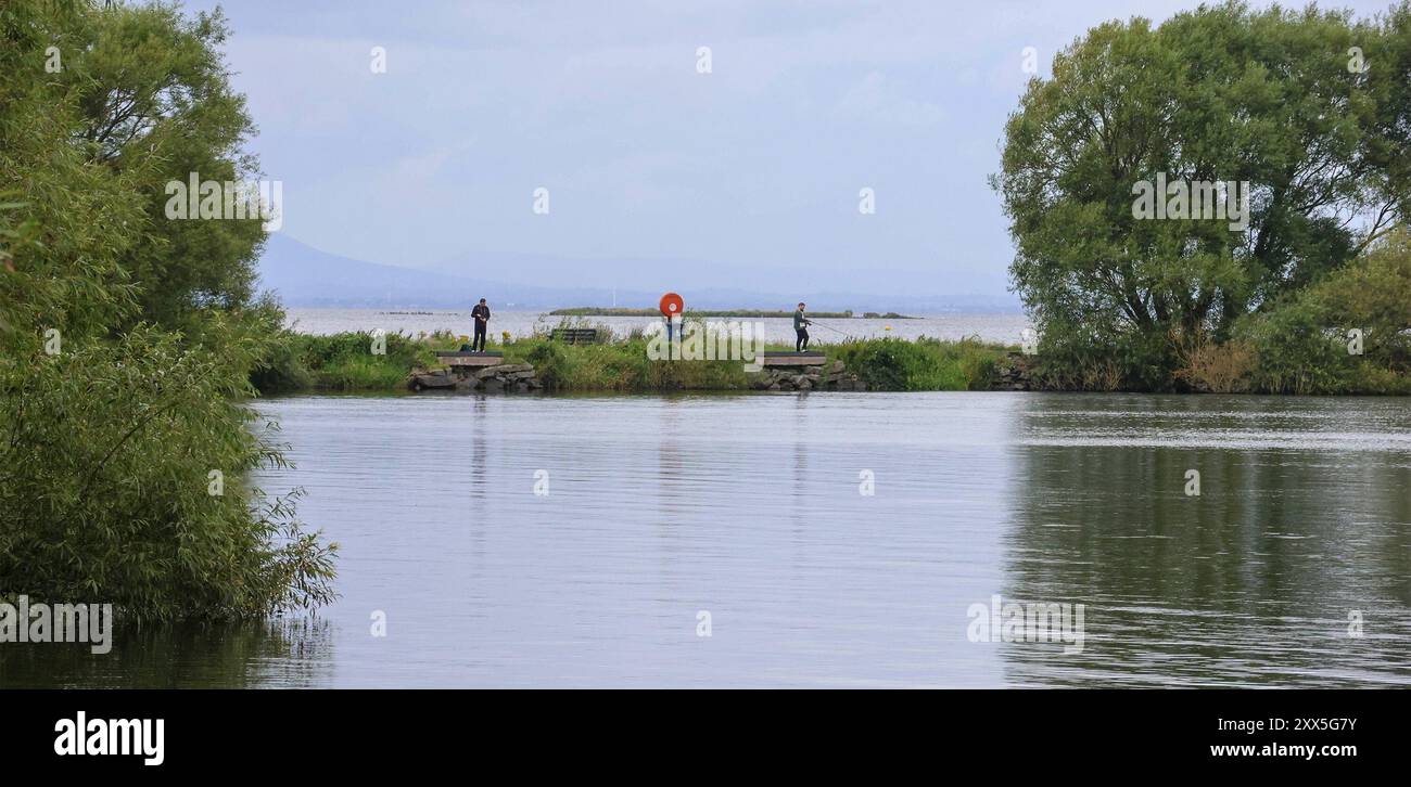 Kinnego, Lough Neagh, County Armagh, Nordirland, Großbritannien. August 2024. UK Weather – ein herbstlicheres Wetter mit grauem Himmel und einer starken Brise, die die Temperaturen in den mittleren Teenagern erreicht. Mehr Wind und Regen werden über Nacht erwartet. Zwei Angler, die sich im ruhigen und geschützten Wasser der Kinnego Marina um Hecht drehen. Quelle: CAZIMB/Alamy Live News. Stockfoto