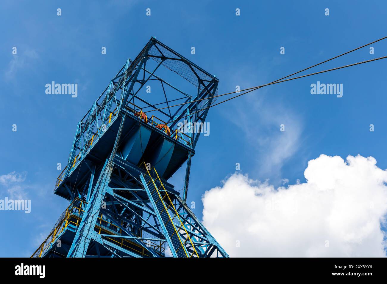 Blauer Kohlebergwerksschacht vor blauem Himmel mit zarten Wolken. Verringerung der Gewinnung fossiler Brennstoffe zugunsten erneuerbarer Brennstoffe Stockfoto