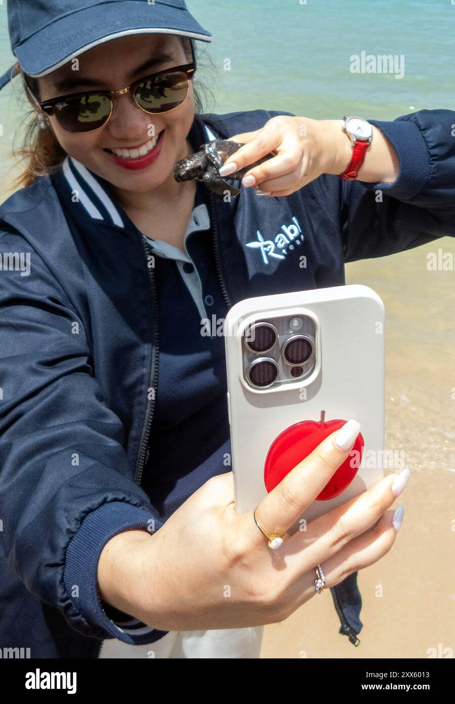 Ein Besucher sah, wie er Selfies mit Meeresschildkröten-Schlüpflingen machte, bevor er sie am Strand des Sea Turtle Conservation Center wieder ins Meer brachte. Das Sea Turtle Conservation Center der Royal Thai Navy wurde gegründet, um vier Arten von Meeresschildkröten in Thailand zu schützen und zu erhalten: Die Lederschildkröte, die grüne Schildkröte, die Karettschildkröte und die Oliven-Ridley-Schildkröte, die alle vom Aussterben bedroht sind. Das Zentrum überwacht die Eiinkubation, hält Meeresschildkröten in ihren frühen Stadien und lässt sie dann wieder in die Wildnis zurück. (Foto: Pongmanat Tasiri/SOPA Stockfoto