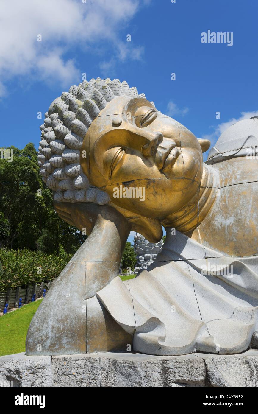 Nahaufnahme einer liegenden Buddha-Statue, die meditative Ruhe vor einem klaren blauen Himmel ausstrahlt, Bacalhoa, Bacalhoa Buddha Eden, Quinta dos Loridos, größte Stockfoto