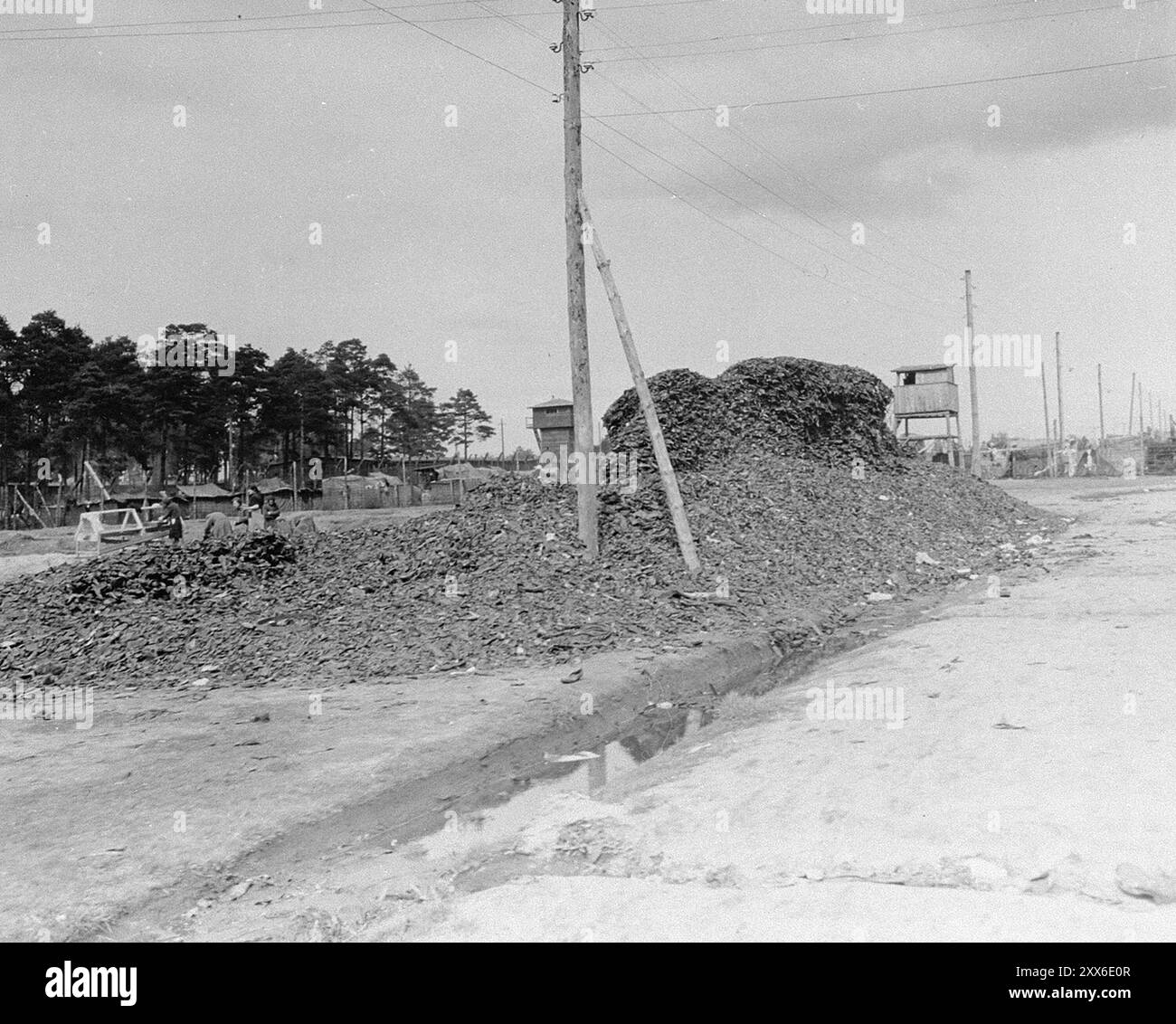 Ein Haufen Schuhe der Opfer auf der Hauptstraße des Konzentrationslagers Bergen-Belsen. Das Foto stammt vom 28. April 1945, zwei Wochen nach der Befreiung des Lagers. Die Lage des Lagers im Westen Deutschlands bedeutete, dass Tausende von Menschen dorthin geschickt wurden, als der Osten fiel. 18000 Menschen starben allein im März 1945, 10000 starben in den zwei Wochen nach der Befreiung. Sie starben eher an Krankheiten und Vernachlässigung als an systematischen Misshandlungen, wie sie anderswo zu beobachten waren. Stockfoto