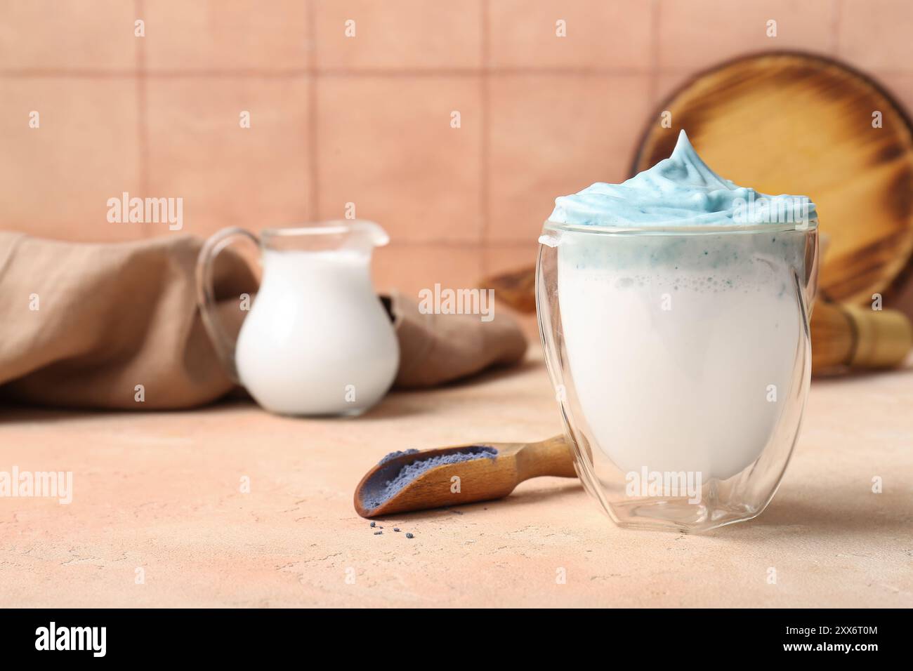 Glas blauer Dalgona Matcha Latte und Löffel mit Matcha Puder auf dem Tisch, Nahaufnahme Stockfoto