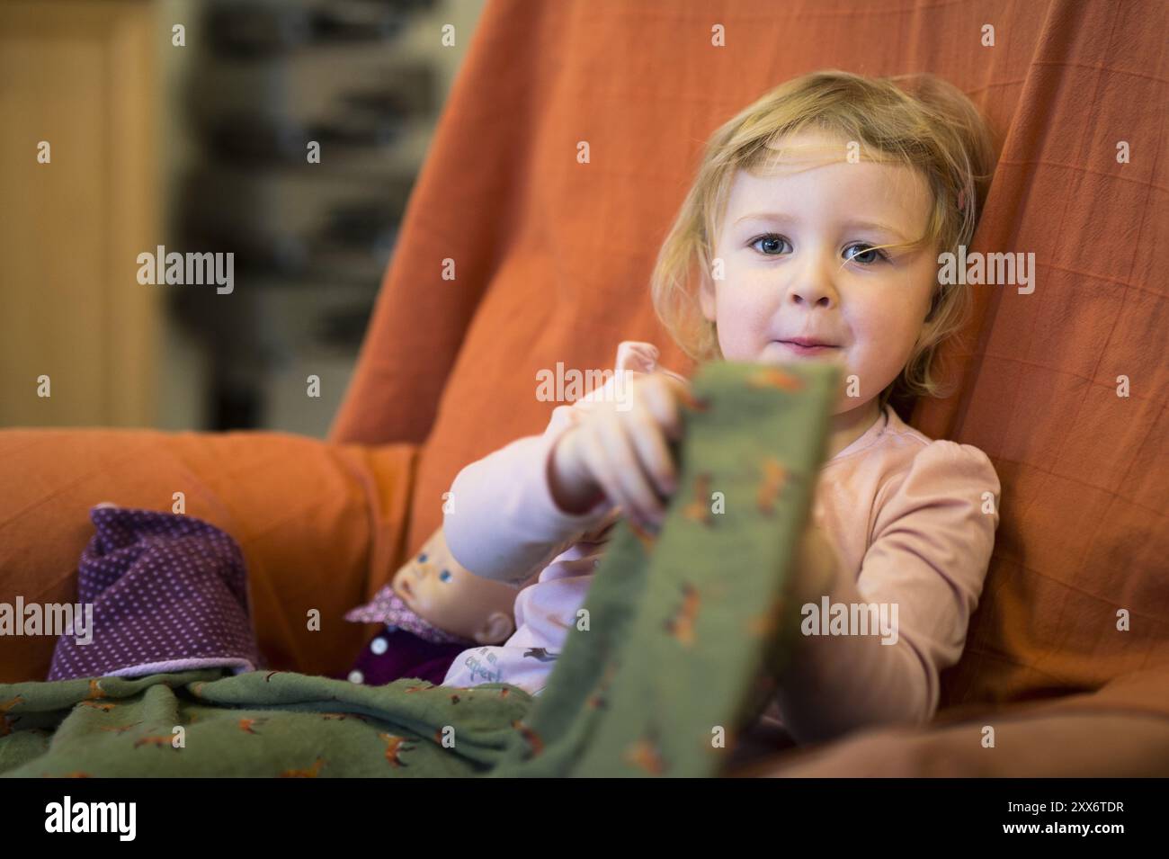 Ein kleines blondes Mädchen sitzt in einem Sessel. Kameraansicht Stockfoto