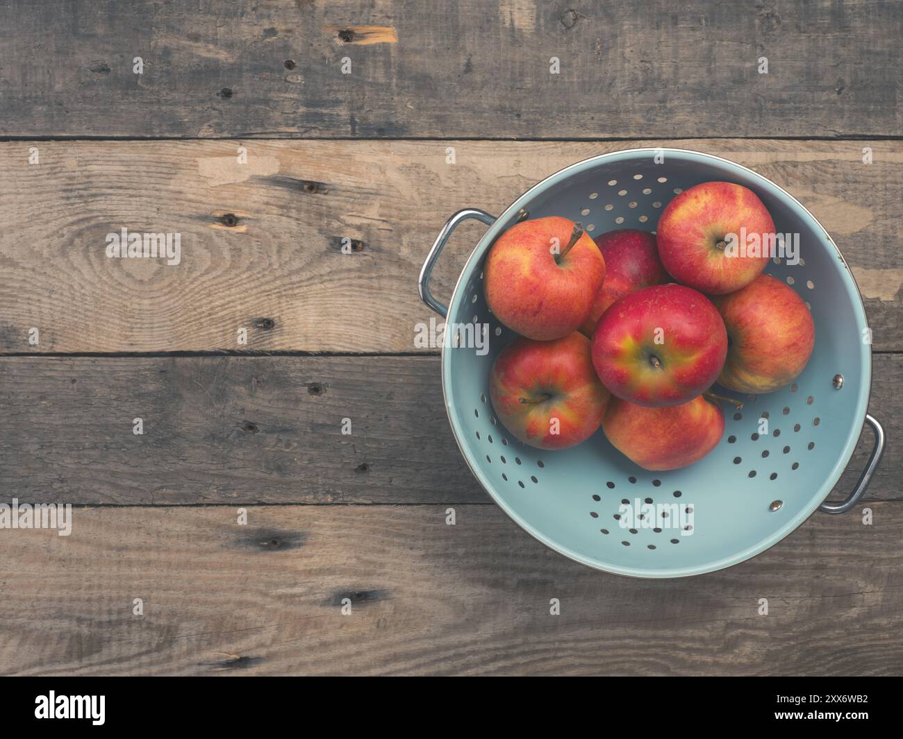 Köstliche Bio-äpfel in einem alten verwendet Sieb auf einem rustikalen Holztisch, Flachbild Ton vintage Stil mit Blick von oben Stockfoto
