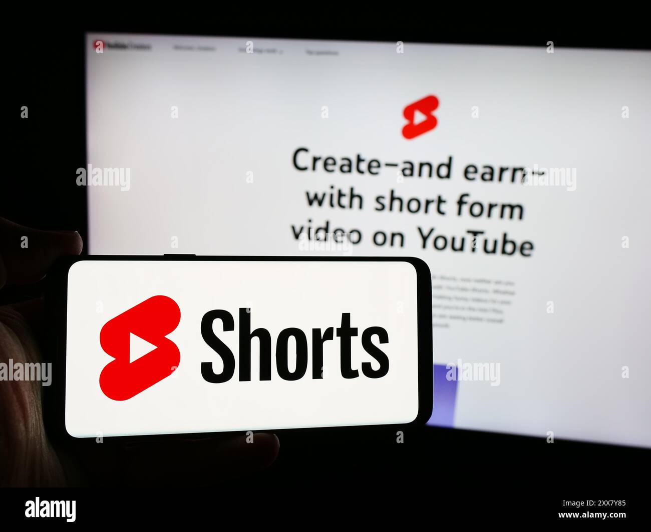 Person, die ein Smartphone mit dem Logo des Short Video Sharing Service YouTube Shorts vor der Website hält. Schwerpunkt auf dem Display des Telefons. Stockfoto