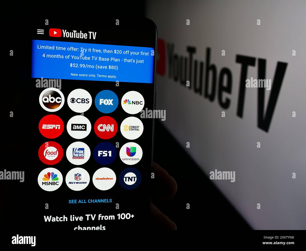 Person, die ein Mobiltelefon hält und die Webseite des US-IPTV-Dienstes YouTube TV vor dem Firmenlogo anzeigt. Konzentrieren Sie sich auf die Mitte des Telefondisplays. Stockfoto