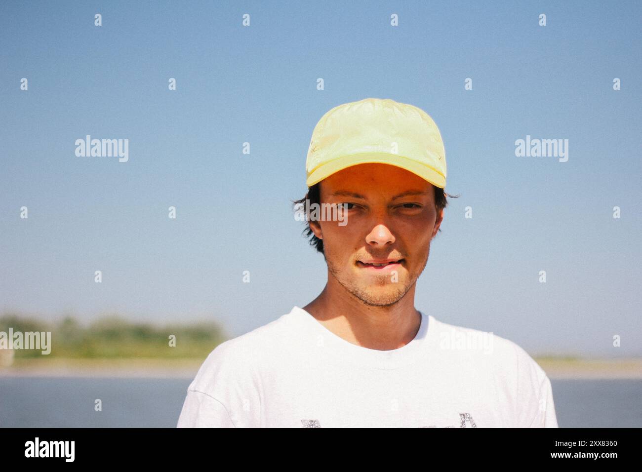 Ein junger Mann mit gelber Mütze genießt einen sonnigen Tag und lächelt. Stockfoto