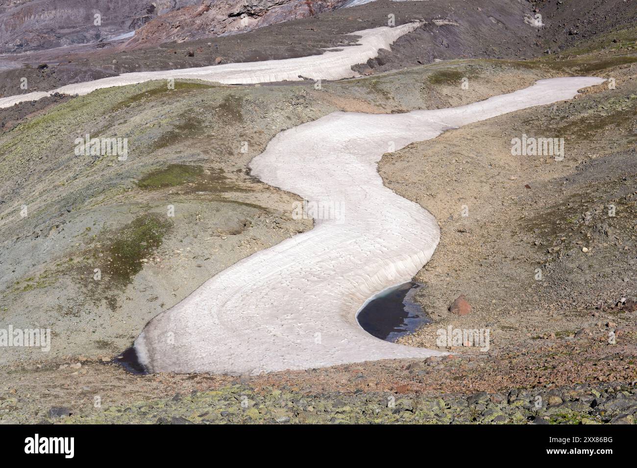 Berglandschaft, felsiges Bett aus schmelzendem Gletscher mit gefrorenem Schmelzwassersee Stockfoto