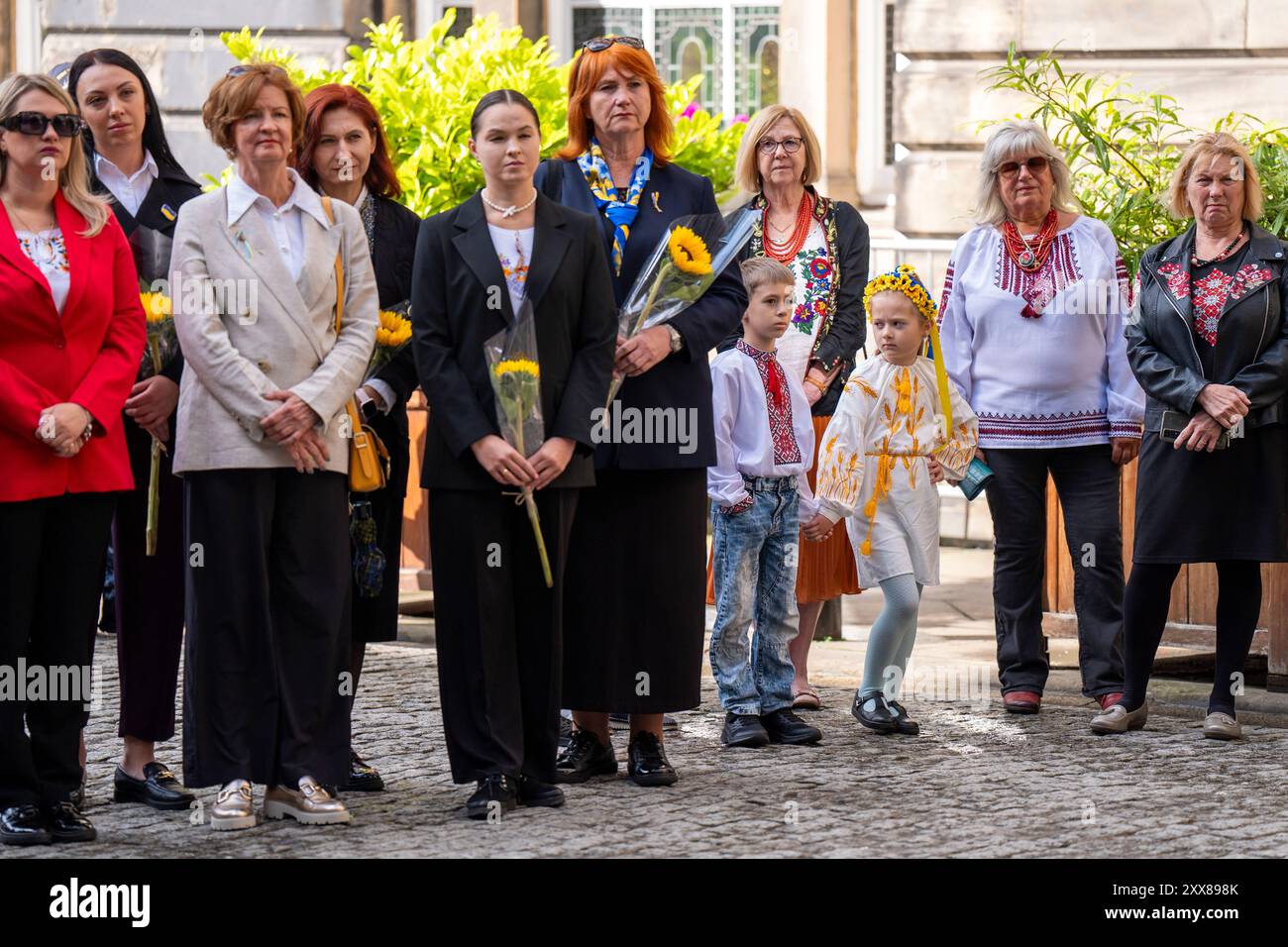 Menschen mit Kränzen und Sonnenblumen am Stone of Remembrance vor den Stadtkammern in Edinburgh während einer Zeremonie zum Unabhängigkeitstag der Ukraine, die am 24. August stattfindet. Mitglieder der ukrainischen Gemeinschaft kommen zusammen, um der Toten des jüngsten Konflikts zu gedenken und auch den Jahrestag der Unterzeichnung der Unabhängigkeitserklärung im Jahr 1991 zu feiern. Bilddatum: Freitag, 23. August 2024. Stockfoto