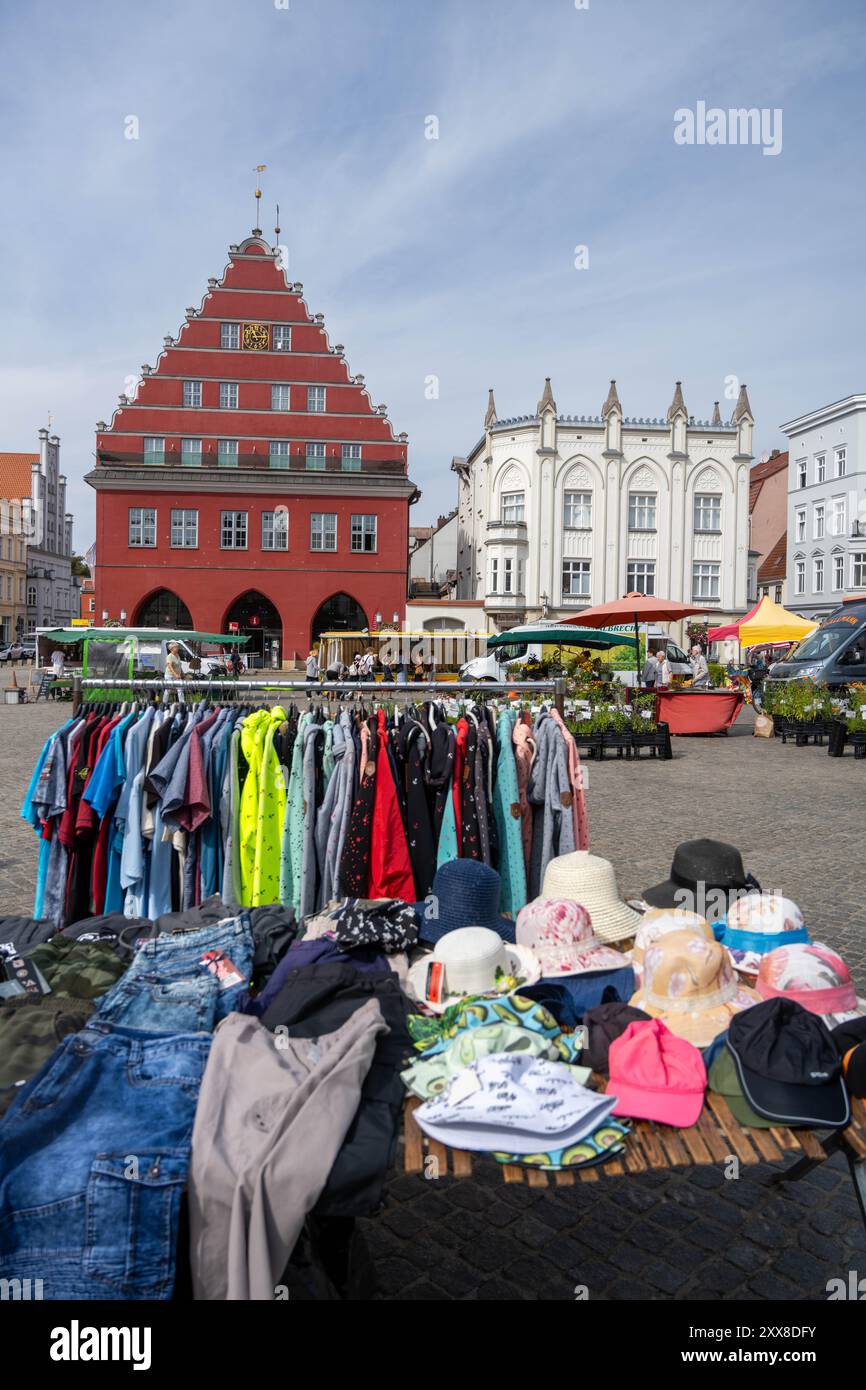 Greifswald, Deutschland. August 2024. Blick über den Markt mit dem Wochenmarkt zum Rathaus (l). Unter dem Motto „Street Art in Friedrichs Zeit“ feiert Greifswald in diesem Jubiläumsjahr an zwei Tagen das Stadtfest zu Ehren von Caspar David Friedrich. Das Festival findet auf dem Marktplatz und an anderen Orten im Stadtzentrum statt. Quelle: Stefan sauer/dpa/Alamy Live News Stockfoto