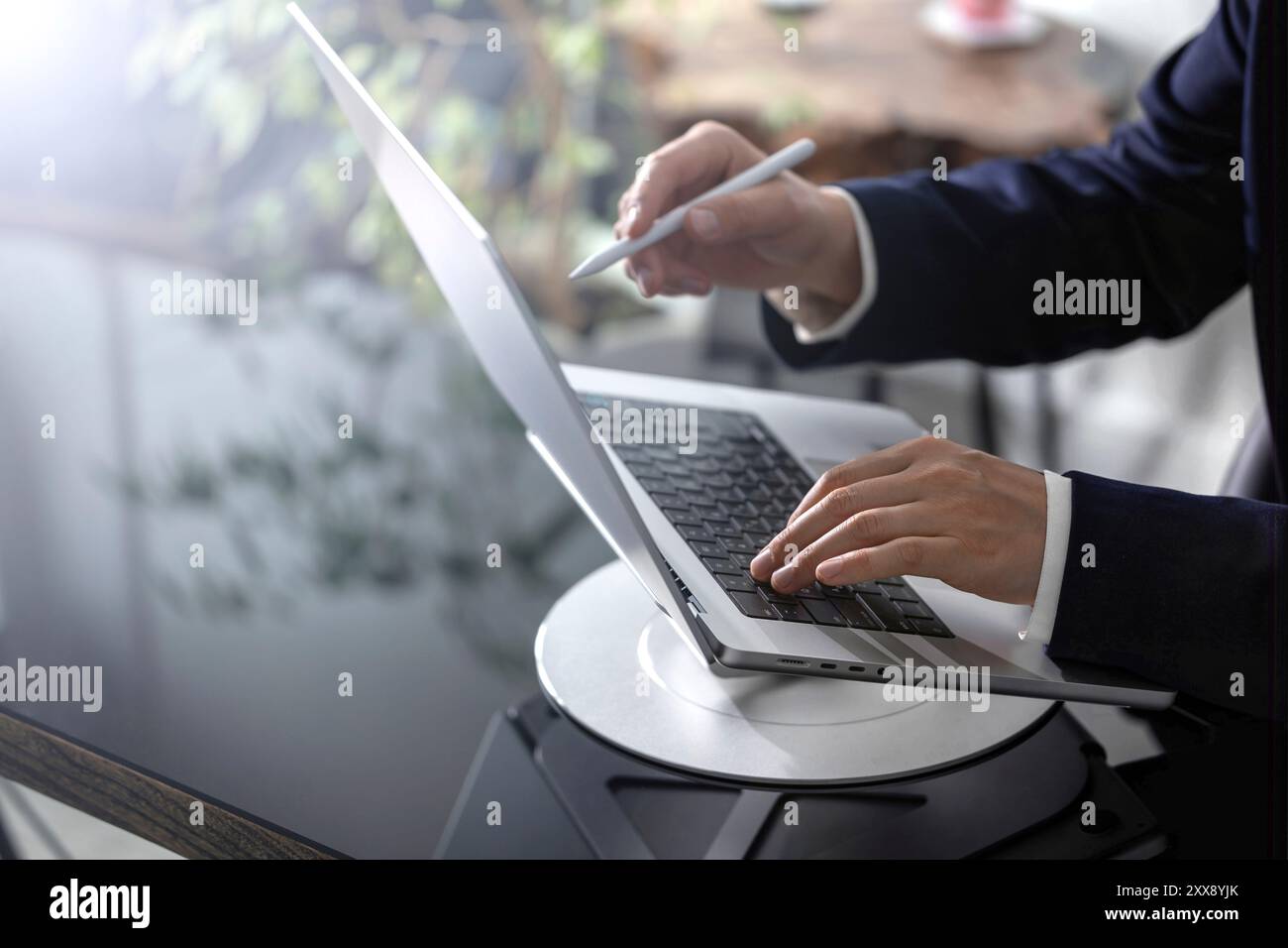 Ein Geschäftsmann konzentriert sich auf sein Notebook am Schreibtisch und ist in seine Aufgaben eingetaucht. Die Büroumgebung ist professionell, mit Dokumenten und wichtigen Aufgaben Stockfoto