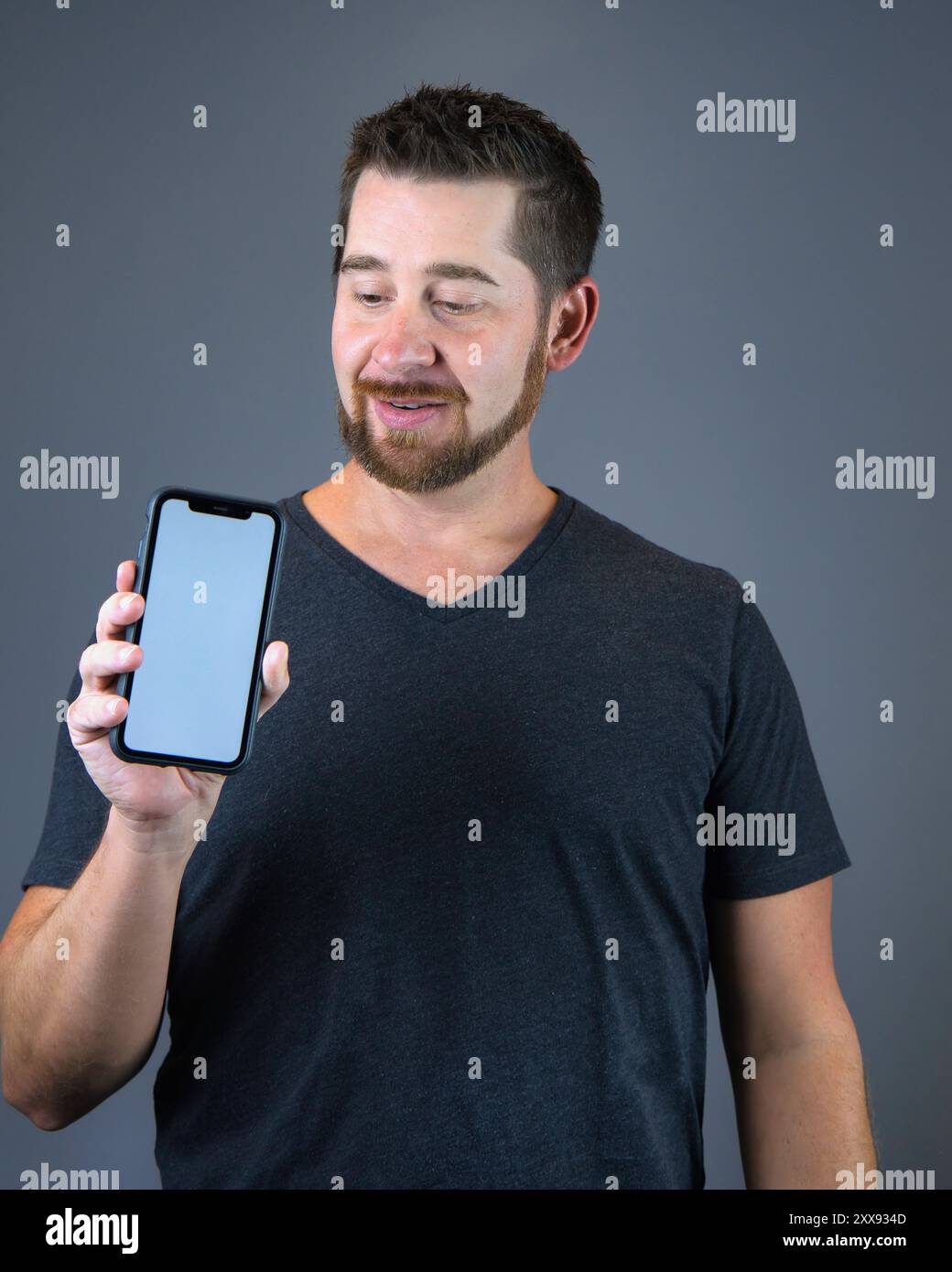 Selbstporträt-Mann, der Smartphone mit leerem Bildschirm für Textüberlagerung hält Stockfoto