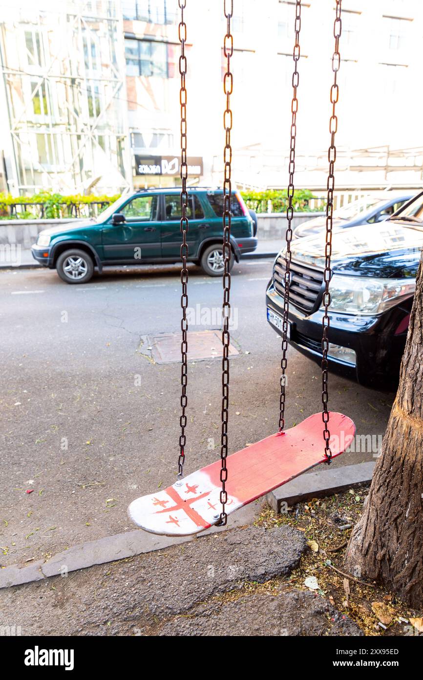 Tiflis, Georgien - 14. August 2024: Altes Skateboard mit georgischer Flagge in einer Straße in Tiflis, Georgien, zu einer Schlinge gemacht. Stockfoto